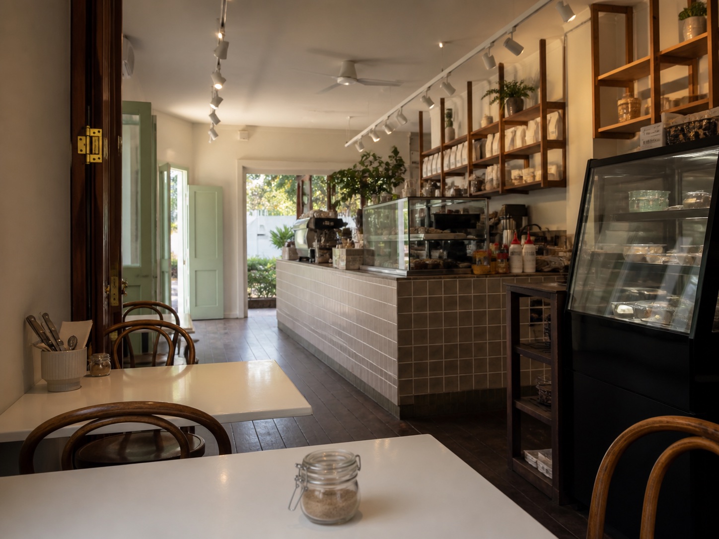 Warm cafe interior with timber chairs, white tables and tiled counter